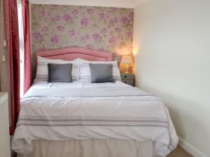 a bedroom with a large bed with a pink headboard at Overland Cottage in Holt