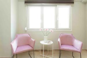 two pink chairs and a table with a vase of flowers at Tsimiski #apartment (one bedroom) in Thessaloniki
