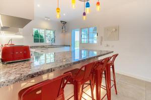 a kitchen with a counter with red bar stools at VILLA OASIS IBIZA in Sant Jordi