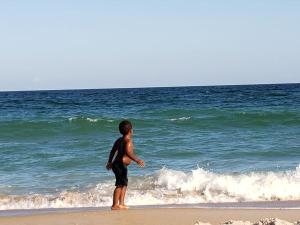 Un ragazzo in piedi sulla spiaggia che guarda l'oceano di 4 Sea Monkeys Apt. #3 a Surf City