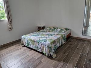 a bedroom with a bed and a wooden floor at La Terrasse des manguiers in Saint-Denis