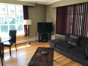 uma sala de estar com um sofá, uma mesa e uma televisão em Leaside Executive Apartments em St. John's