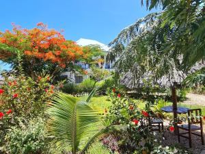 um jardim com mesa, cadeiras e flores em Frangipani House Nungwi Zanzibar em Nungwi