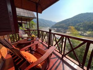 a porch with chairs and a table and a view of a river at Mekong Riverside Lodge in Pakbeng