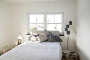 una camera da letto con un letto bianco e cuscini sopra di Loft “Samuel” a Utting am Ammersee