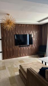 a living room with a couch and a television on a wall at Luxury spacious 3 Bed apt with pool in Agadir
