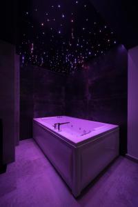 una vasca da bagno bianca in una stanza con illuminazione viola di Rei House Apartmani a Belgrado