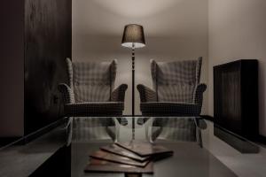 2 sillas y una lámpara sobre una mesa de cristal en Rei House Apartmani, en Belgrado