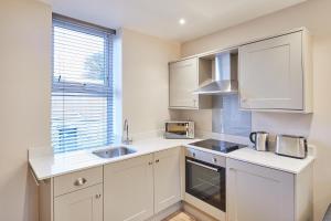 a kitchen with white cabinets and a sink and a window at Host & Stay - Ramblers Retreat in Pateley Bridge