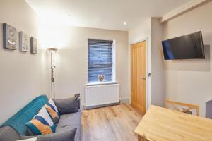 a living room with a couch and a tv on the wall at Host & Stay - Ramblers Retreat in Pateley Bridge