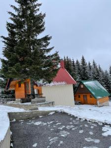 une cabane avec un pin dans la neige dans l'établissement Bungalows Krstajić, à Žabljak