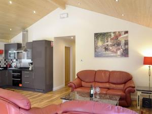 a living room with two leather couches and a kitchen at Maple Lodge in Otterburn