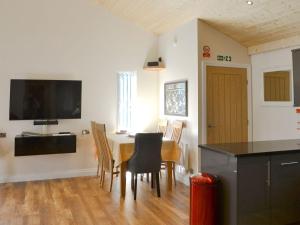 a dining room with a table with chairs and a flat screen tv at Maple Lodge in Otterburn