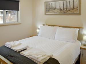 a bedroom with a bed with white sheets and pillows at Maple Lodge in Otterburn