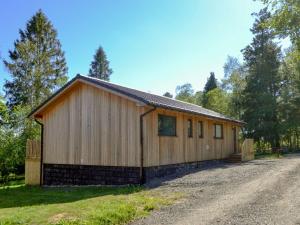 a large wooden building on the side of a dirt road at Maple Lodge in Otterburn
