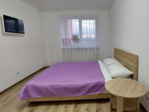1 dormitorio con cama morada y mesa en Яровиця з Кондиціонером,Центр, en Lutsk