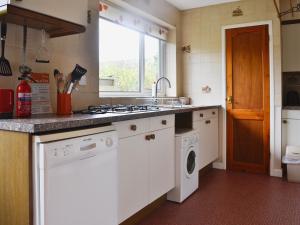a kitchen with a sink and a washing machine at Sunshine Cottage in Fairford