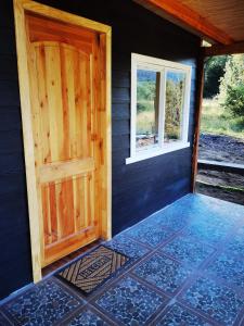 una puerta y una ventana en el lateral de una casa en Cabañas Orillas Del Nilahue, en Riñinahue