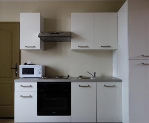 a white kitchen with a microwave and a stove at Adéloïa Cottage in Fauverney +57 photos