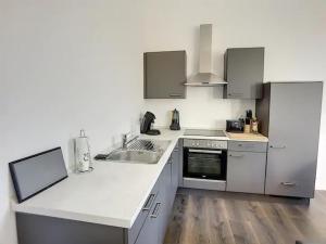 - une cuisine avec des comptoirs blancs, un évier et une cuisinière dans l'établissement Appartement 021, à Liège