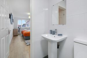 a white bathroom with a sink and a mirror at Pinewood Studios, Iver Slough Heathrow 1 & 2 Bedroom Apartments with Parking by Arista Living in Slough