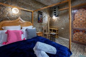 a bedroom with a bed and a stone wall at Riad Mosaic in Chefchaouene