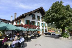 un groupe de personnes assises à des tables devant un bâtiment dans l'établissement Alpengasthof zur Post, à Schattwald