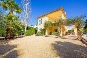 a yellow house with a palm tree and a yard at Villa Gio - PlusHolidays in Calpe