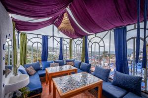 シェフシャウエンにあるRiad Mosaicの青いソファと大きな窓が備わる客室です。