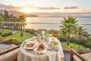 a table with food and a view of the ocean at Les Suites at The Cliff Bay - PortoBay in Funchal