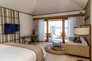 a bedroom with a bed and a television and a desk at Kagi Maldives Resort & Spa in North Male Atoll