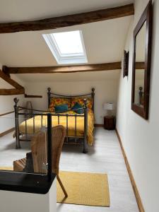 een slaapkamer met een bed en een dakraam bij Virolet Barn in Queaux