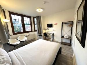 a bedroom with a white bed and two chairs at Sleeplicity London Heathrow in Feltham