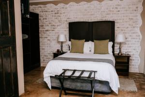 a bedroom with a large bed and a brick wall at La Bendicion in eMalahleni