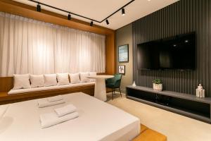 1 dormitorio con 1 cama blanca grande y TV de pantalla plana en WI-FI 200MB | Piscina no Rooftop #CORG01, en Florianópolis