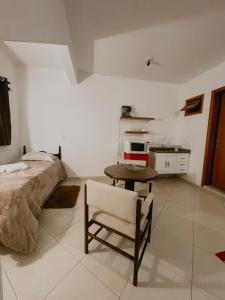 a bedroom with a table and a bed and a kitchen at Apartamento Girassol 2 coruja in Camanducaia