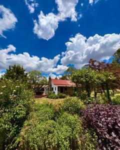 a house with a blue sky and clouds at Red Hill Cottage Walcha in Walcha