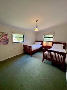 1 dormitorio con 2 camas y 2 ventanas en Red Hill Cottage Walcha en Walcha