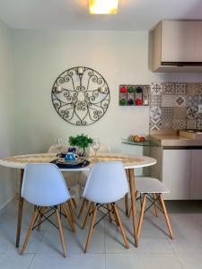 a kitchen with a table and white chairs at Solar Água Pipa 119 in Pipa