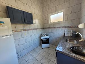a small kitchen with a sink and a refrigerator at Pousada Genoveva - Apto com um dormitório in Farol de Santa Marta