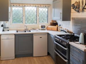 a kitchen with a sink and a stove top oven at Apple Tree Cottage in Charmouth