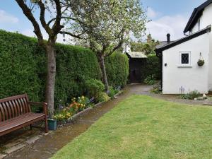 a park bench in a garden with flowers at Apple Tree Cottage in Charmouth