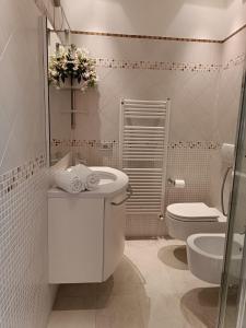 La salle de bains blanche est pourvue de toilettes et d'un lavabo. dans l'établissement Patty ZU - Lakeside apartment, à Riva di Solto