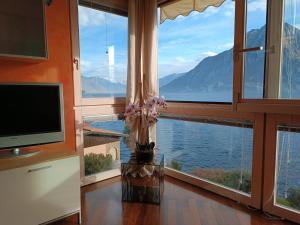a room with a large window with a view of the water at Patty ZU - Lakeside apartment in Riva di Solto