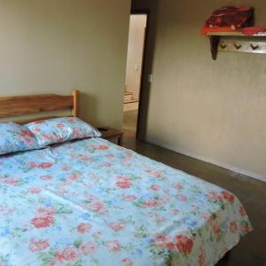 1 Schlafzimmer mit einem Bett mit Blumenbettdecke in der Unterkunft Pousada Fernandes in Aratuba