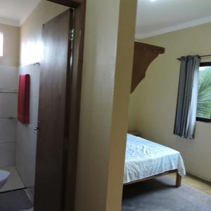ein Schlafzimmer mit einem Bett und ein Badezimmer mit einer Dusche in der Unterkunft Pousada Fernandes in Aratuba
