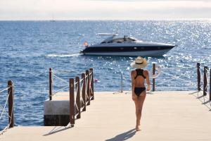 a woman in a bikini walking down a dock with a boat at Les Suites at The Cliff Bay - PortoBay in Funchal