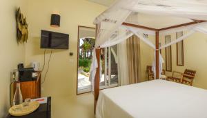 a bedroom with a canopy bed and a television at Alma Boutique Hotel in Jambiani +37 photos