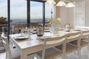 a dining room with a white table and chairs and windows at STAR APARTMENTS in Cape Town