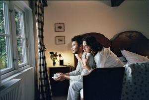 a man and woman sitting on a bed playing a video game at Panorama-Loft Fehmarn mit Meerblick in Fehmarn